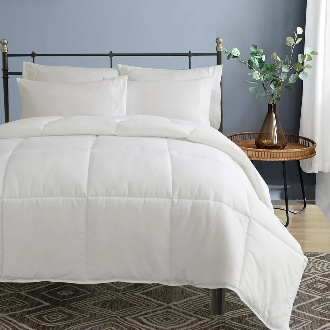 a bed with white comforter and pillows