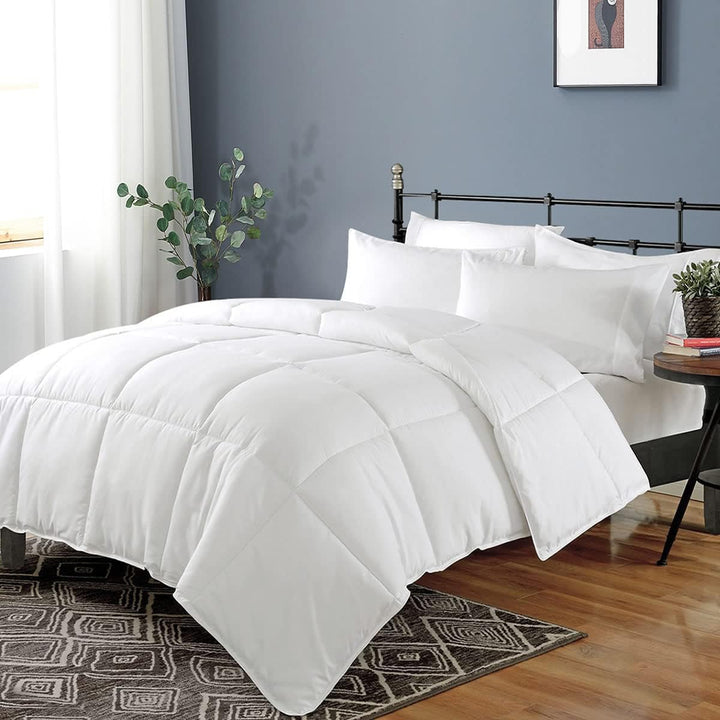 a bed with white comforter and pillows