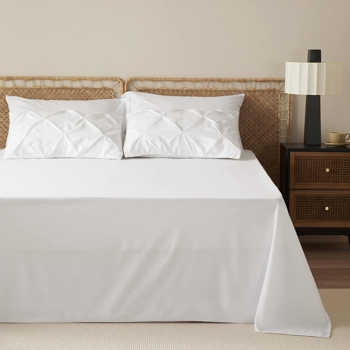 a bed with white sheets and a lamp next to a nightstand