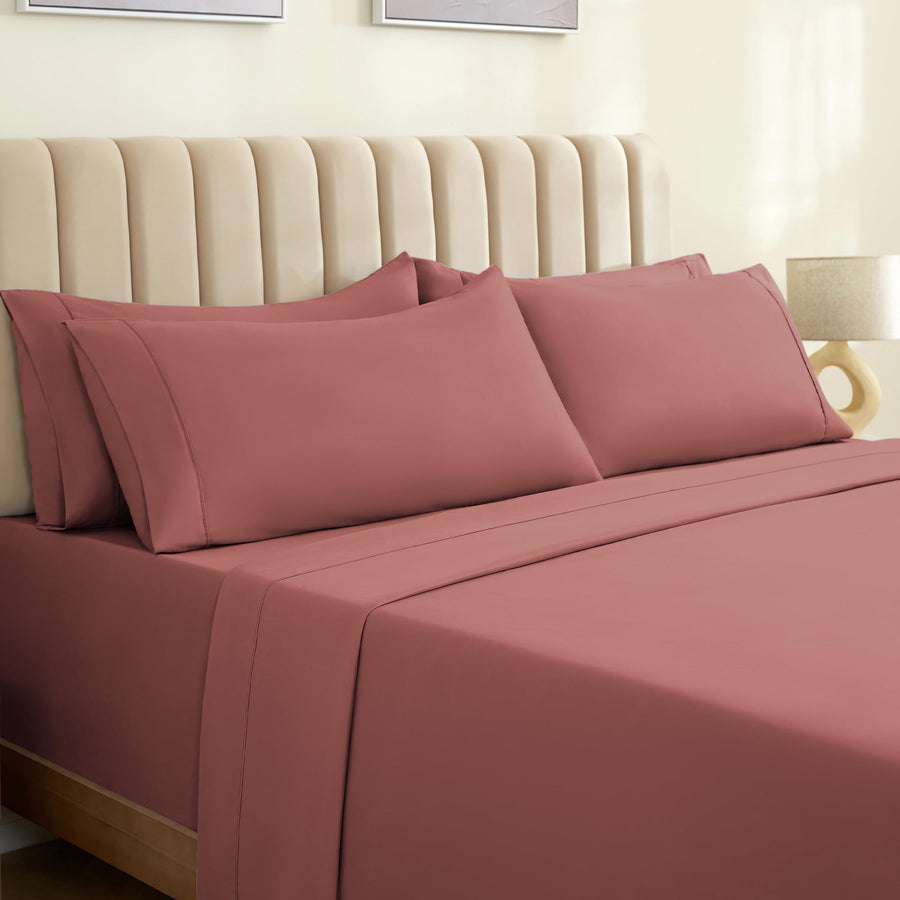 a bed with pink sheets and a white headboard