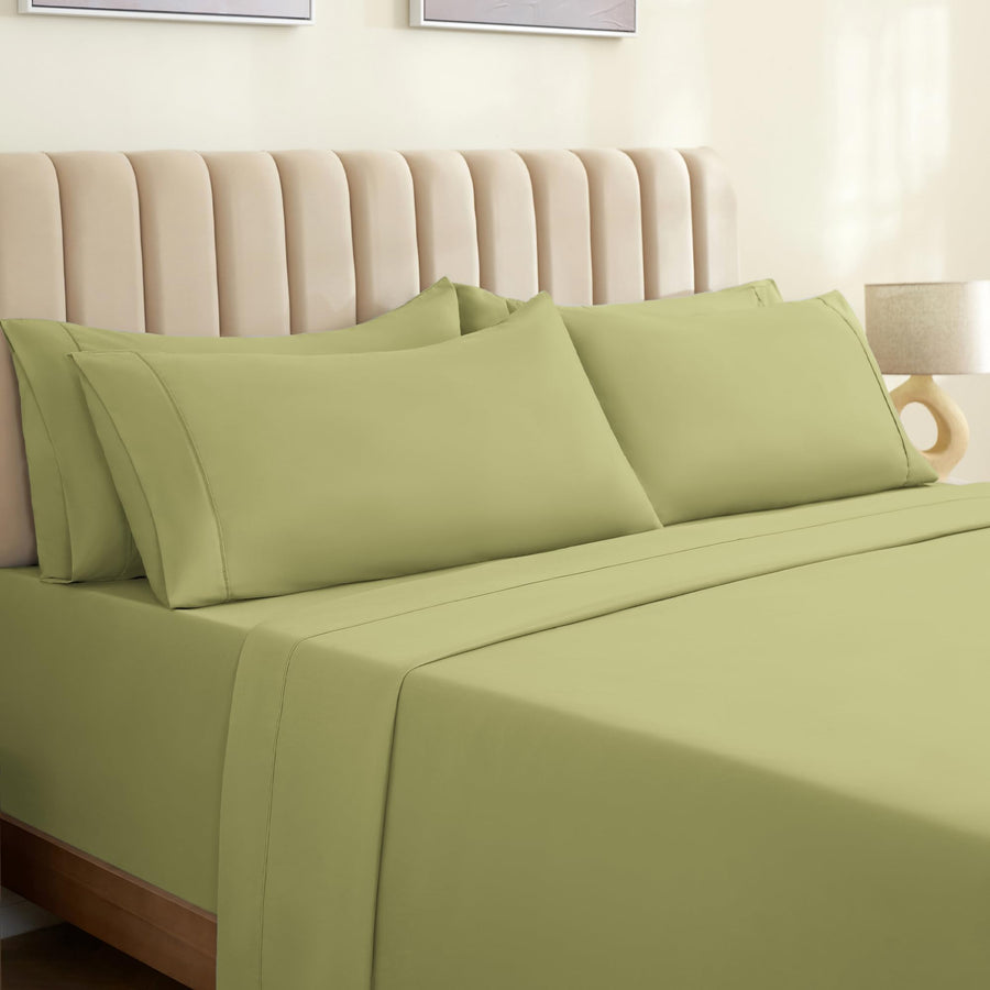 a bed with green sheets and a lamp